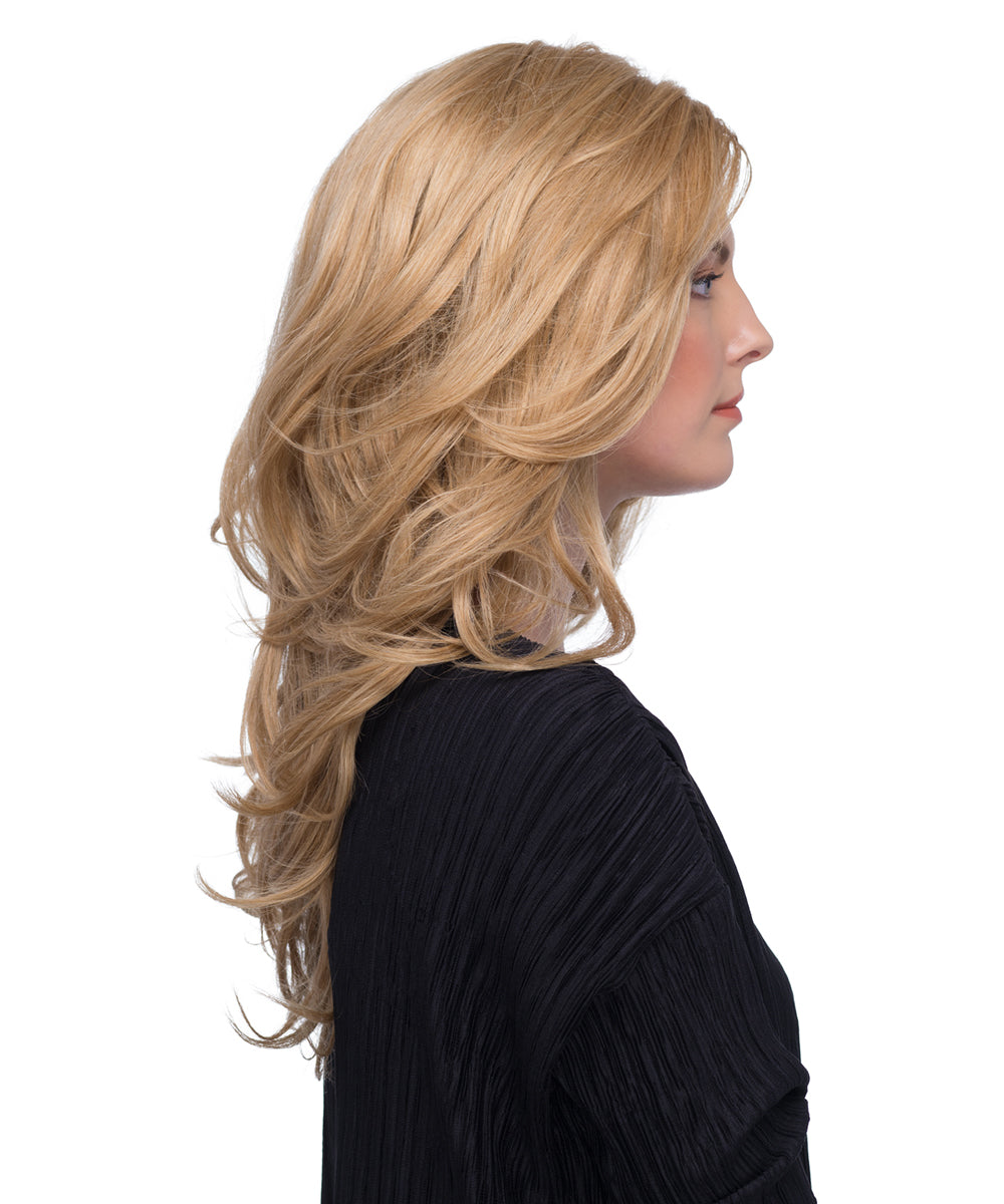 Woman wearing long blonde wig styled in loose waves, wearing a black top on a white background