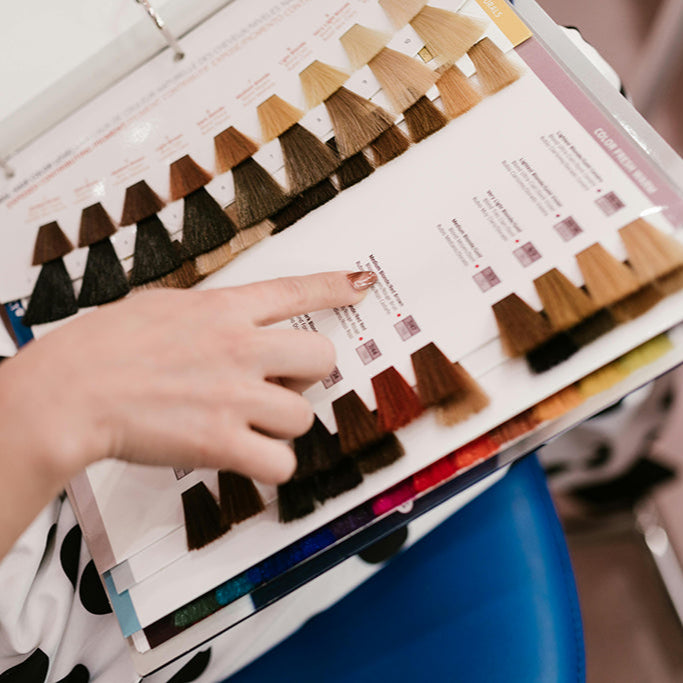 Person selecting hair color swatches from a hair color chart